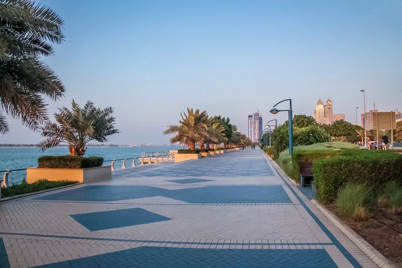People walking and cycling along a waterfront promenade in the early evening