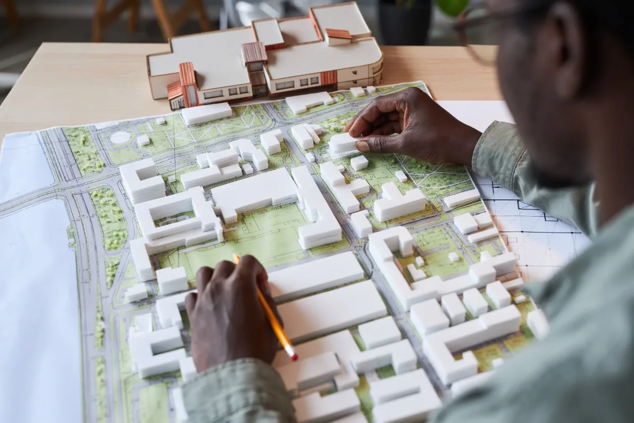 A planner placing white massing blocks on a site plan of roads, plots and green space
